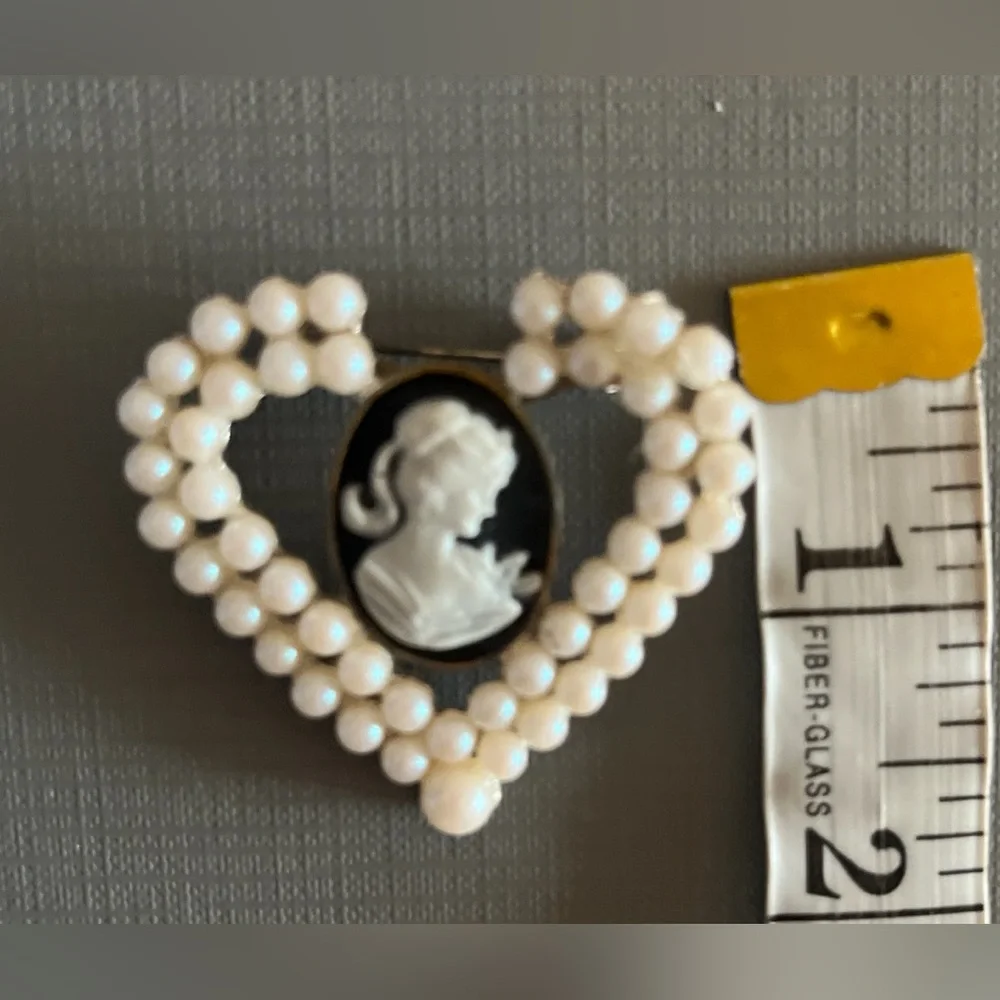 Vintage heart-shaped brooch featuring a black and white cameo with faux pearls.